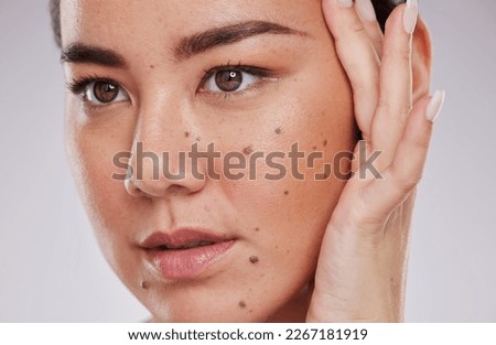Beauty, face and skincare of a woman in studio for makeup, dermatology and cosmetics for skin glow. Aesthetic asian model person with hand to show mole and facial self care for health and wellness