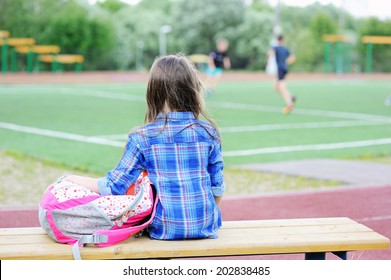 Beauty  Fashion Brunette School Age Kid Girl In The Blue Plaid Shirt, Jeans Skirt And Yellow Scarf Writing In Her Notepad Outdoor On The Playground