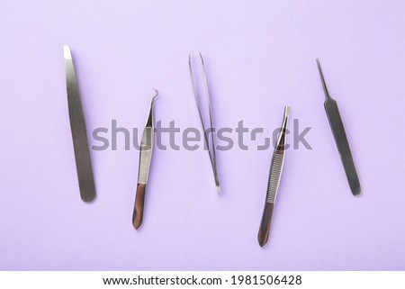 Beauty and fashion concept - tools for Eyelash Extension Procedure. Tweezers on purple background. Copyspace mockup. Top view