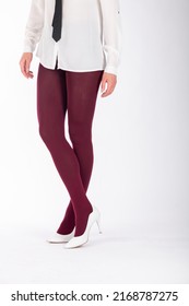 Beauty and fashion concept. Woman beautiful legs wearing burgundy color tights and classic white high heel shoes on white studio background with copy space. Models with white shirt and black ties