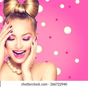 Beauty Fashion Happy Model Girl With Funny Bow Hairstyle, Pink Nail Art And Makeup Over Polka Dots Background. Laughing Retro Styled Young Woman