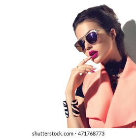 Beauty Fashion model girl with brown hair wearing stylish sunglasses. Sexy woman portrait with perfect makeup and manicure, trendy accessories and fashion wear. Beauty trends. Isolated on white