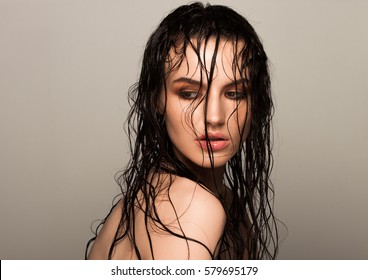 Beauty fashion model girl natural makeup wet hair  on grey background in warm tones