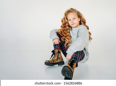 Beauty Fashion Portrait Of Smiling Curly Hair Tween Girl In Cozy Knitted Sweater And Plaid Pants On White Background 