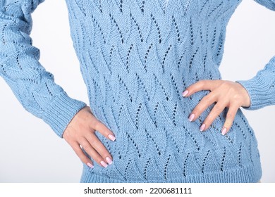 Beauty, Fashion And Style Concept. Close-up Studio Shot Of Woman Torso With Blue Sweater. Beautiful Model Body Shape. Studio Shot With Copy Space. Hand Placed On Belly With Pink Manicure