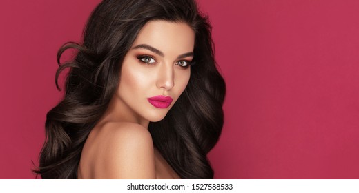 Beauty Fashion Woman Brunette Portrait With Brown Eyes And Healthy Long Shiny Wavy Black Hair. Volume Shampoo. Attractive Model With Professional Make Up Against Red Background