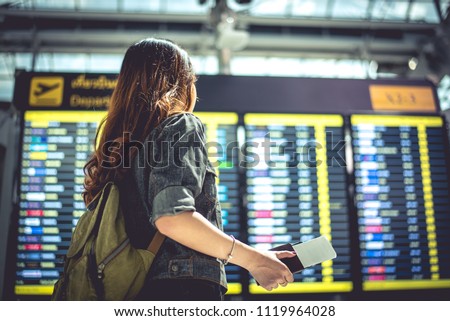 Beauty female tourist looking at flight schedules for checking take off time. People and lifestyles concept. Travel and Happy life of single woman theme. Back view portrait.