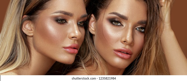 Beauty and femininity concept. Two attractive twins women in glamour makeup. Portrait photo.