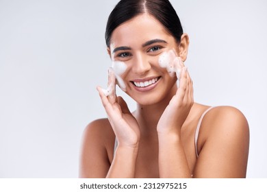 Beauty, foam wash and portrait of a woman in a studio for natural, cosmetic and skincare routine. Wellness, smile and female model cleaning her face with facial cleanser isolated by white background