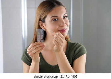 Beauty girl applying acne treatment anti-pickel patch on a pimple in bathroom at home