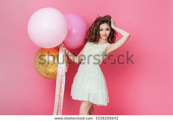 ピンクの背景に笑うカラフルな風船を持つ美女 誕生日のお祝いパーティーで美しい幸せな若い女性 パステルカラー風船で楽しみ 遊び 祝うファッションモデル の写真素材 今すぐ編集