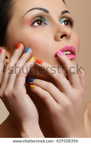 Beauty Girl Face with Colorful Nail polish. Colourful Studio Shot of young Woman