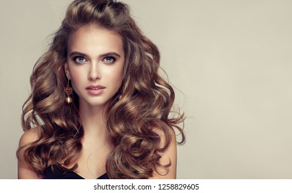 Beauty girl with long  and   shiny wavy hair .  Beautiful   woman model with curly hairstyle .