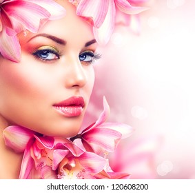 Beauty Girl With Orchid Flowers.Beautiful Model Woman Face. Perfect Skin. Professional Make-up.Makeup. Fashion Art