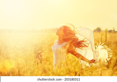 Beauty Girl Outdoors enjoying nature. Beautiful Teenage Model girl in white dress running on the Spring Field, Sun Light. Glow Sun. Free Happy Woman. Toned in warm colors - Powered by Shutterstock