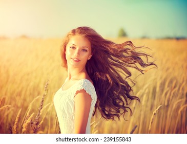 Beauty Girl Outdoors enjoying nature. Beautiful Teenage Model girl with long healthy blowing hair running on the Spring Field, Sun Light. Glow Sun. Free Happy Woman. Toned in warm colors