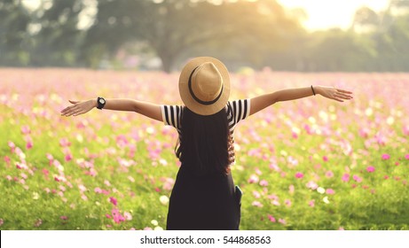 Beauty Girl Outdoors enjoying nature. Beautiful Teenage Model girl in black dress standing  on the Spring Field, Sun Light. freedom concept