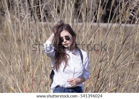 Beauty girl in sunglasses and white shirt on on wild nature