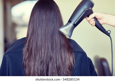 beauty, haircare, blow-dry, hairstyle and people concept - stylist hand with fan dries woman hair at salon