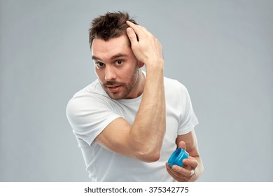 Beauty, Hairstyle, Haircare And People Concept - Happy Young Man Styling His Hair With Wax Or Gel Over Gray Background