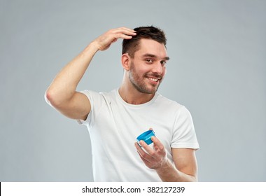 Beauty, Hairstyle, Haircare And People Concept - Happy Young Man Styling His Hair With Wax Or Gel Over Gray Background