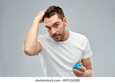 Beauty, Hairstyle, Haircare And People Concept - Happy Young Man Styling His Hair With Wax Or Gel Over Gray Background