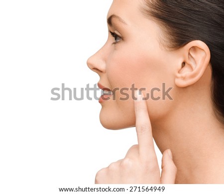 beauty and health concept - smiling young woman pointing to her cheek