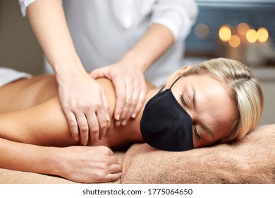 Beauty And Health Safety Concept - Woman Wearing Face Medical Mask For Protection From Virus Lying With Closed Eyes And Having Hand Massage In Spa