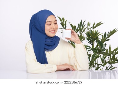 Beauty Hijab Woman's Left Hand Holds White Jar Bottle And Look At It With Smiling