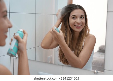 Beauty at home. Smiling young woman applying dry shampoo on her hair. Fast and easy way to keep hair clean with dry shampoo. Hair care. - Powered by Shutterstock