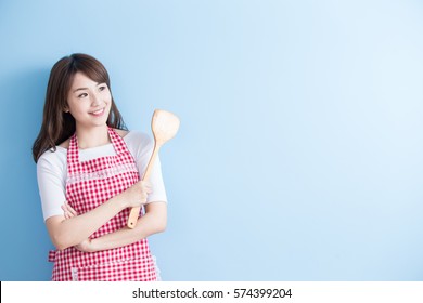 beauty housewife take rice spoon and look somewhere isolated on blue background
