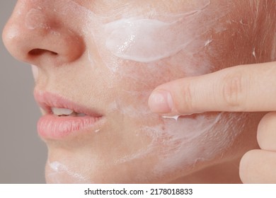 Beauty image of pretty shirtless woman smiling and applying face cream, isolated over beige background - Shutterstock ID 2178018833