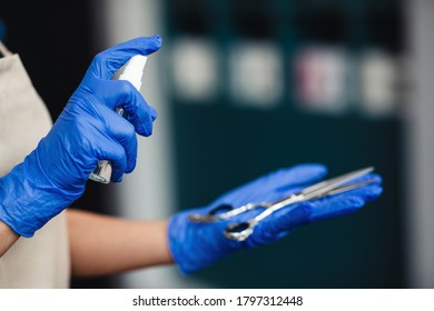 Beauty industry and hygiene. Master in medical gloves spraying disinfectant on scissors, close up - Powered by Shutterstock