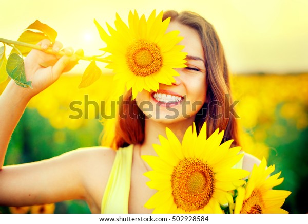 ひまわりを楽しみ 夏のひまわり畑で笑う ひまわりを持つ 美しい10代の女の子 太陽の光 太陽の光 太陽の光 バックライト の写真素材 今すぐ編集
