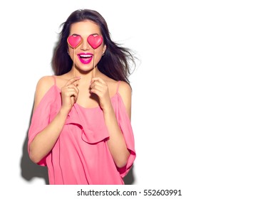 Beauty joyful Young fashion model Girl with Valentine Heart shaped cookies in her hands. Love Concept. Beautiful smiling young woman. Valentines Day gift. Isolated on white background.