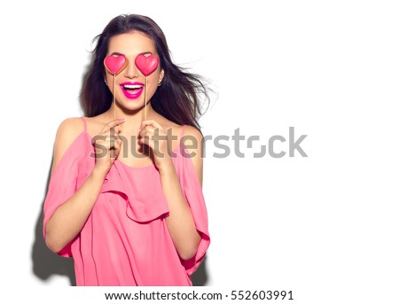 Beauty joyful Young fashion model Girl with Valentine Heart shaped cookies in her hands. Love Concept. Beautiful smiling young woman. Valentines Day gift. Isolated on white background.
