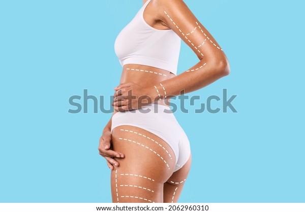 Beauty, Lifting, Anti-age And Tightening\
Concept. Closeup cropped view of young woman in white top and\
panties posing with massage lines and arrows on her full body,\
isolated on blue studio\
background