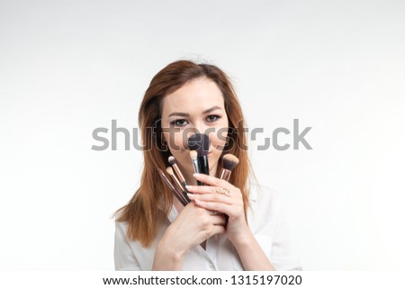 Beauty makeup artist. Portrait of korean beautiful young woman pretty smiling fooling around with make-up brushes on white background.