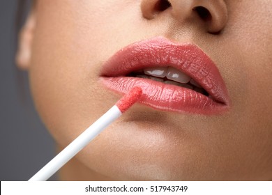 Beauty Makeup. Closeup Of Beautiful Woman Face With Smooth Skin, Soft Plump Full Lips With Lip Gloss On. Close-up Of Girl Applies Liquid Lipstick Or Lip Balm, Lip Care Cosmetics. High Resolution Image