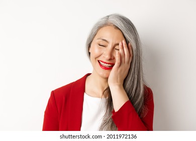 Beauty And Makeup Concept. Close Up Of Beautiful Asian Mature Woman, Laughing And Touching Face, Smiling Happy, Standing Over White Background