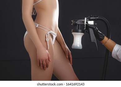 Beauty Master Applying Fake Tan On Woman`s Body. Ekotanning. Ecological Tan. Female Making Tanning In Tan Studio. Client Making An Express Bronzing By Airbrush-pistol.