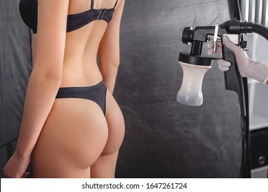 Beauty Master Applying Fake Tan On Woman`s Body. Ekotanning. Ecological Tan. Female Making Tanning In Tan Studio. Client Making An Express Bronzing By Airbrush-pistol.