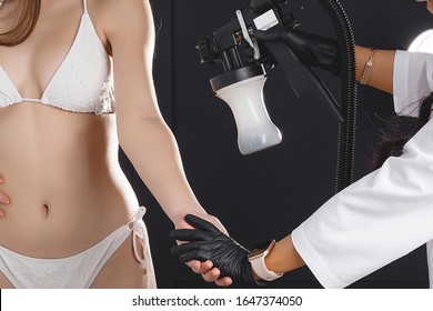 Beauty Master Applying Fake Tan On Woman`s Body. Ekotanning. Ecological Tan. Female Making Tanning In Tan Studio. Client Making An Express Bronzing By Airbrush-pistol.