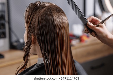 beauty master combing client's wet hair in beauty salon close-up, self-care concept, professional hair care