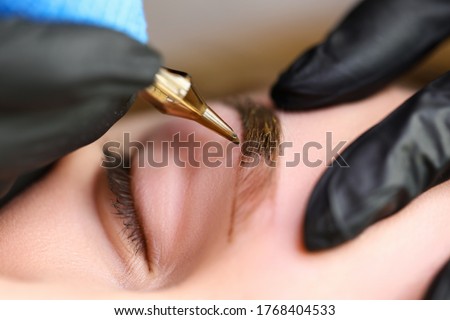 Beauty masters hands do permanent eyebrow makeup. Minimal trauma to skin. Eyebrow microblading is performed using manipulator handle and special nozzle with needles. Cosmetologist skill level