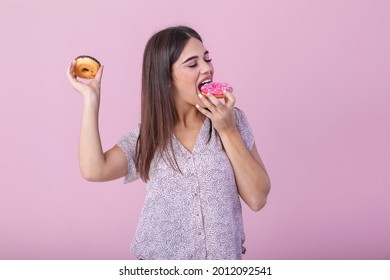 Beauty Model Girl Eating Colorful Donuts. Funny Joyful Vogue Styled Woman Choosing Sweets On Pink Background. Diet, Dieting Concept. Junk Food, Slimming, Weight Loss