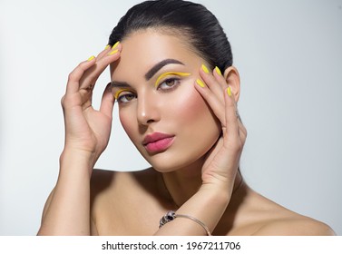 Beauty model girl with fashion make-up, Bright yellow eye line and nails, trendy manicure. Eye make-up creative ideas. Summer makeup. Beautiful young woman portrait. Face closeup