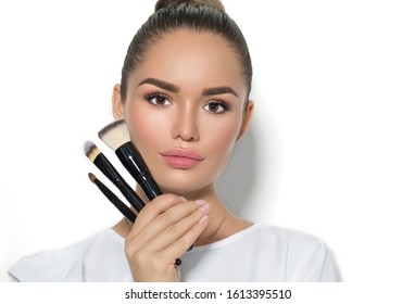 Beauty Model Girl, Makeup Artist Holding Set Of Make Up Brushes And Smiling. Beautiful Brunette Young Woman With Perfect Skin And Nude Make-up. Perfect Skin Closeup. Face Contouring Makeup. On White