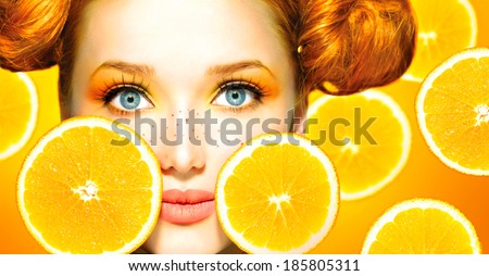 Beauty Model Girl takes Juicy Oranges. Beautiful Joyful teen girl with freckles, funny red hairstyle and yellow makeup . Professional make up. Orange  Slices 