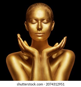 Beauty Model with Golden Shining Skin. Woman Face with Closed Eyes and open Hands Palms. Gold Art Portrait over Black